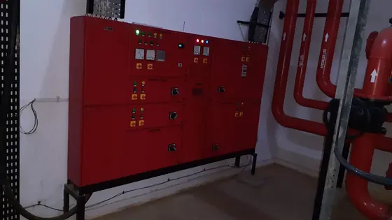 Red fire pump control panel installed beside fire water pipework